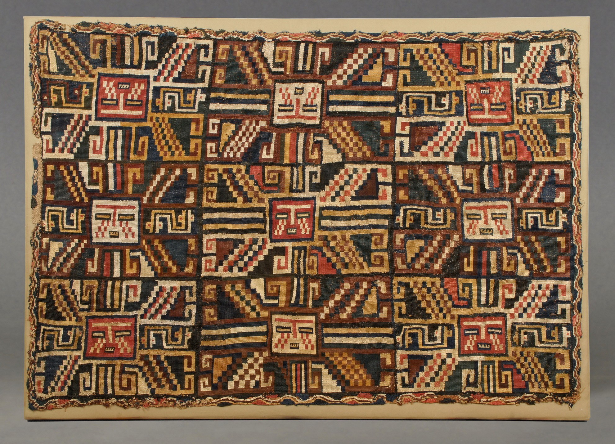 Peru, Sihuas Mantle with nine sun faces
The Sihuas sun face image was derived from the Tiwanaku Moon god. On this textile, the images are arranged  3 x 3 alternating in red and white sun faces. Rare double interlocking warp and weft with edges finished in the original pattern of a complicated oblique weave. According to Jorge Haeberle who has studied Sihuas textiles, this is one of only three known garments of this type. He thinks it was a head cloth with the opposing row of faces folded over from front to back showing the sun faces right side up on the front of the forehead. This weaving is very complicated and from the earliest Sihuas phase around 300 - 100 BC. There have been several larger Sijuas textiles with just a single sun face, while this one with the rows of faces compares to or perhaps influenced early known Tiwanaku and Pucuara weavings. The Sihuas complex of weaving began about 500 BC and was contemporany with Paracas embroideries. The Sihuas culture was eventually absorbed by the Nazca in the seventh century.
Media: Textile
Dimensions: 37 1/2" x 46"
Price Upon Request
MM801