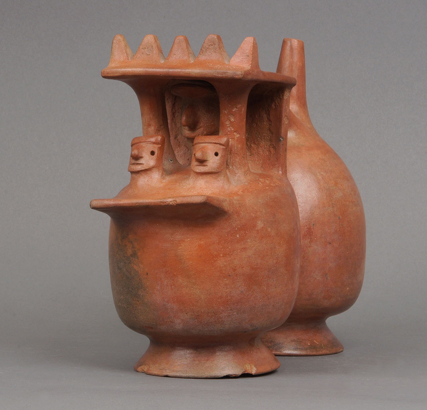 Peru, Virú Double Chambered Single Spout Whistling Vessel in the Form of a Temple
A strap handle orangeware vessel of a temple with lord and two attendants.  The two heads could also be architectural elements or trophy heads. There are traces of negative resist decoration. Larco Hoyle describes and llustrates similar shaped vessels in his monograph "Cronologia del Norte de Peru, La Cultura Virú" (1945: 4 and 8).
Media: Ceramic
Dimensions: Height 8" Length 7 1/2"
$4,500
92080