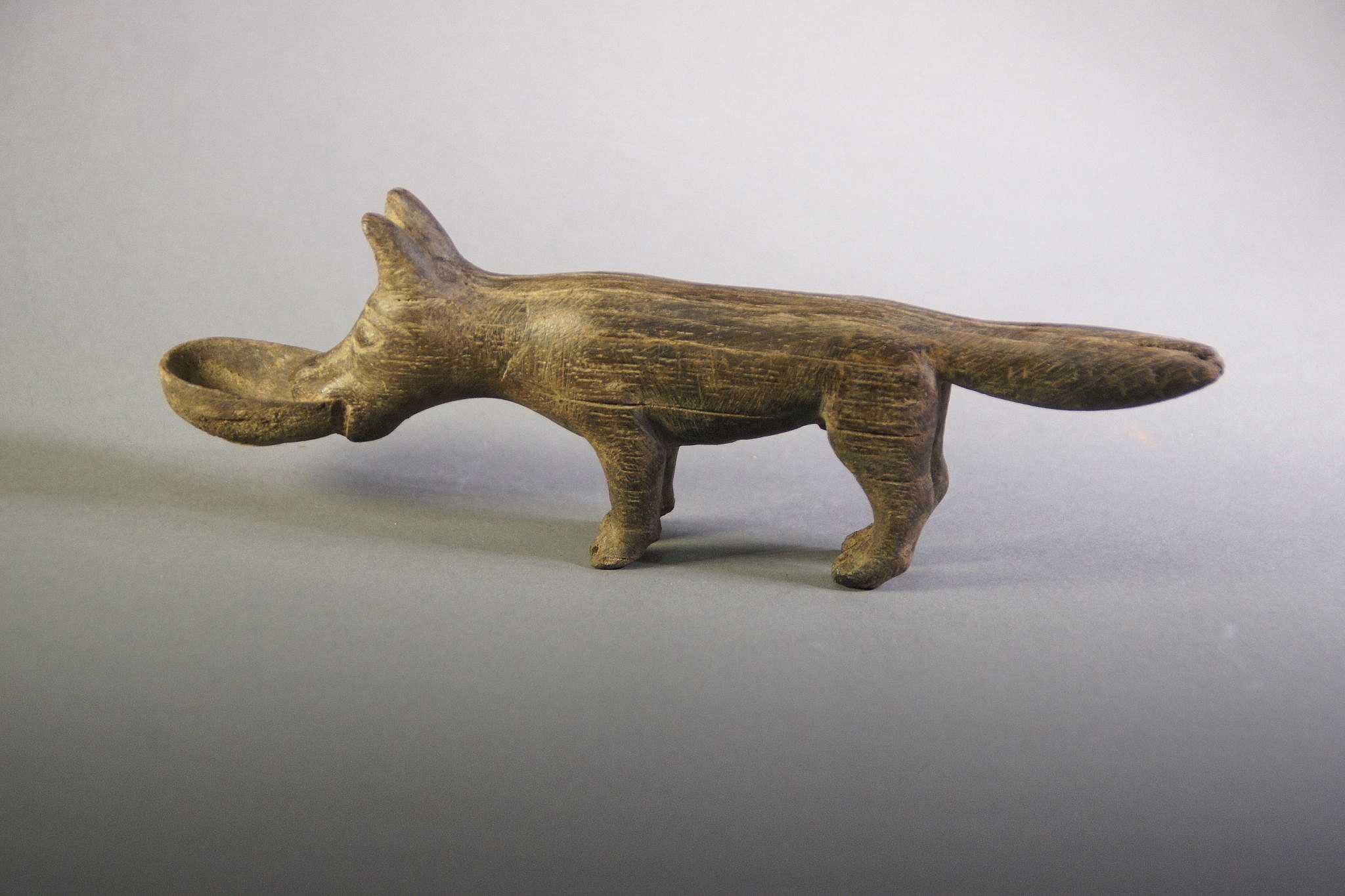 Peru, Wari Carved Wooden Dog with Bowl in Mouth
The dog has a fluffy tail and is holding a bowl in its mouth, asking for food.
Media: Wood
Dimensions: Length: 7"
Price Upon Request
N3033