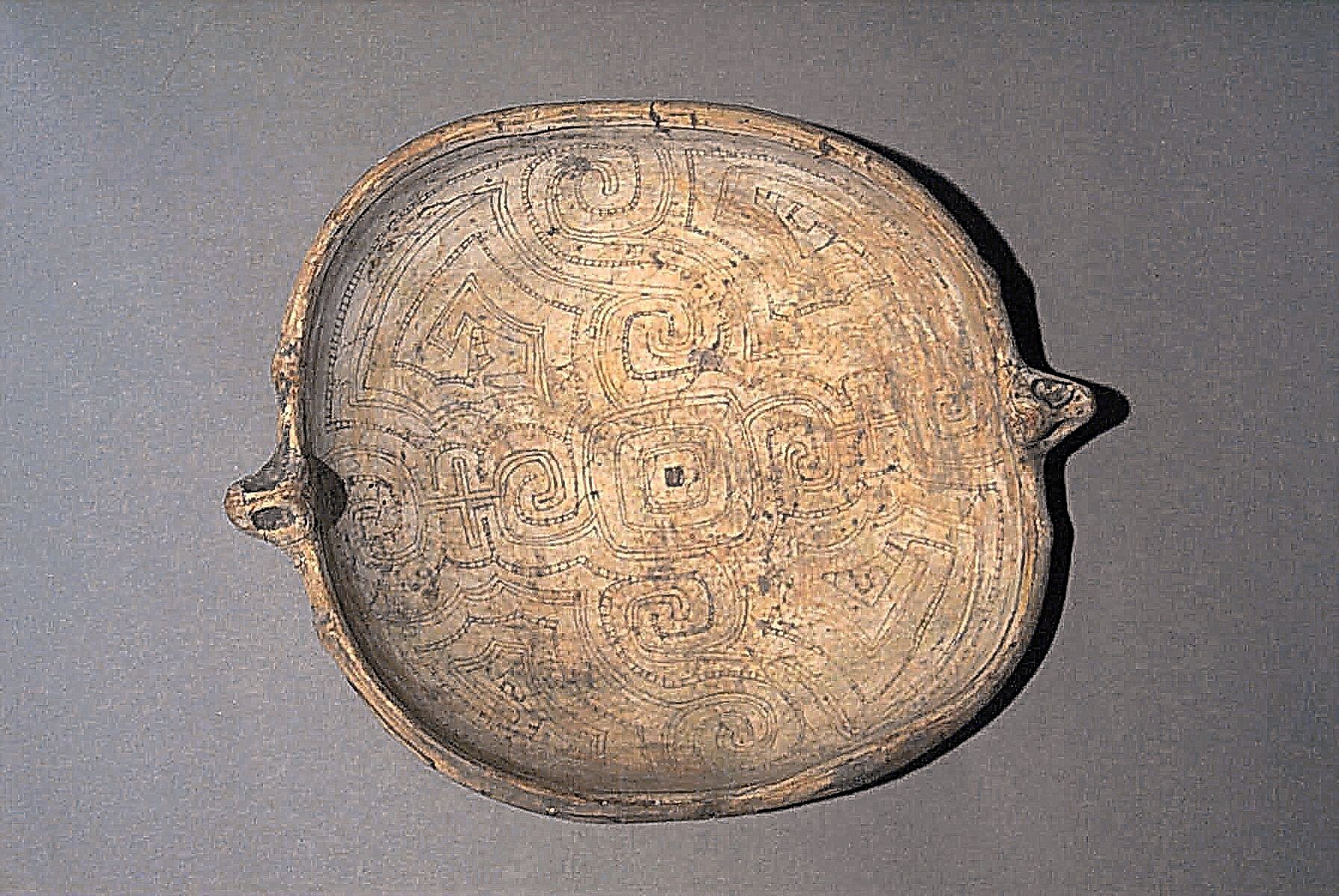 Brazil, Marajo Plate with incised geometric design and zoomorphic handles
Ceramic dish used for ceremonial offerings is decorated in buff color slip over incised geometric curvilinear designs on the interior and underside of the rim which is embellished by two zoomorphic adorno handles. The overall shape suggests a possible interpretation of a turtle, an animal  motif that appears frequently in Marajo ceramics. The fineline incised geometric pattern that decorates the interior begins with a central theme of a square within the square which is surrounded by S-shaped scrolls, hooks and cruciform designs.  These types of geometric motifs which occur exclusively on ceremonial vessels designate this as a very special dish.  A combination of fine and wide incised geometric lines decorate the outer portion of the rim.  The underside is plain orange-wear. The painted incised interior, a hold-over from earlier phases is consistent with the design work from early Taino ceramics of the Carribean.  One example illustrating similar geometric design and incising technique can be seen in"O Museu Paraense Emilio Goeldi", Banco Safra, 1986, p. 133
Media: Ceramic
Dimensions: Length: 13" x Width: 10 1/4"
$9,500
99203