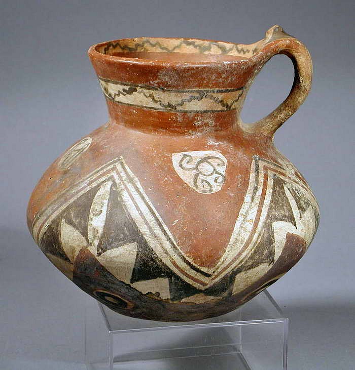 Chile, Arica Lug Handled Pitcher with geometric designs in black, white and red
San Miguel style white and black on red slip ground. The geometric design consists of four white circles inside a red ground, and underneath are a undulating bands of lines and triangles. Below this are black and white  concentric cirles, and  black and white bands inside and around the spout. The colors and designs are similar to a vessel illustrated in Cultures De Chile Prehistoria, Chile (1997: 196-a and d), and Excavations in Northern Chile by Junius Bird (1943: 199-jand f ). 
Media: Ceramic
Dimensions: Height 6 1/2" x width 8"
$1,500
M3011