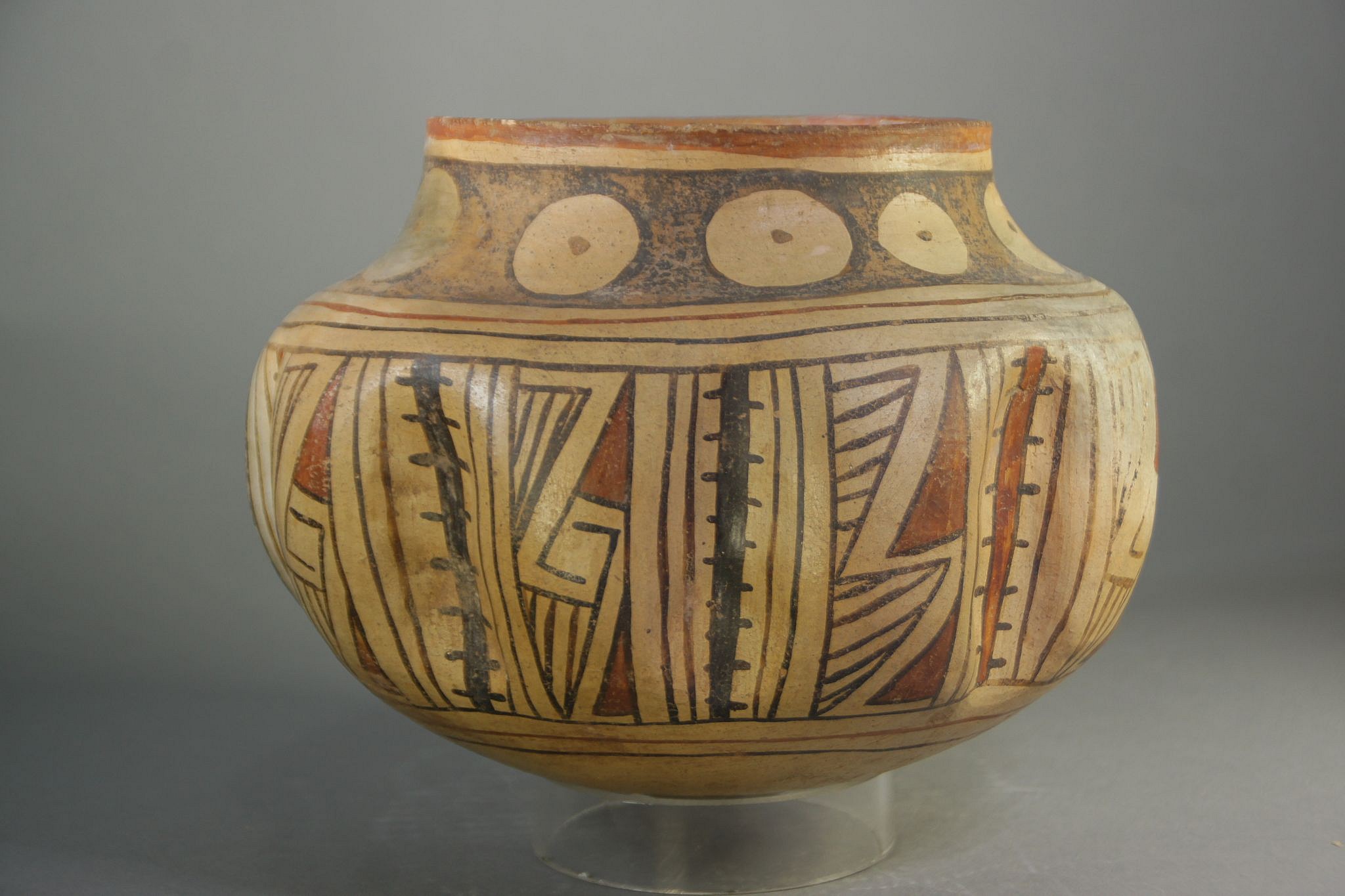 Mexico, Casas Grande Fluted Ceramic Vessel with Geometric Designs
This unusual ceramic bowl has nine fluted sections separated by symbolic cacti imagery.  The bowl is painted with red and black geometric designs on a beige ground.  On the bottom are three large concentric black lines.  It has a tapered neck that is decorated with nine beige circles on a black ground.  Each circle has a central black dot, which believe symbolizes an aerial view of a cactus.  This vessel originates from Casas Grande, a site located in the Mexican state of Chihuahua, along the Casas Grande River and South of the US Puebloan ruins.  A good reference is â€œCasa Grandes and the Ceramic Art of the Ancient Southwestâ€ by Richard Townsend, published by the Art Institute of Chicago.
The bowl is in good condition with one crack on the bottom restored and a small hole on one of the fluted sections.
Period: Mexico, Casas Grande Classic Period  c. AD 1250 - 1475
Media: Ceramic
Dimensions: H. 6" x W. 8"
Price Upon Request
n6012