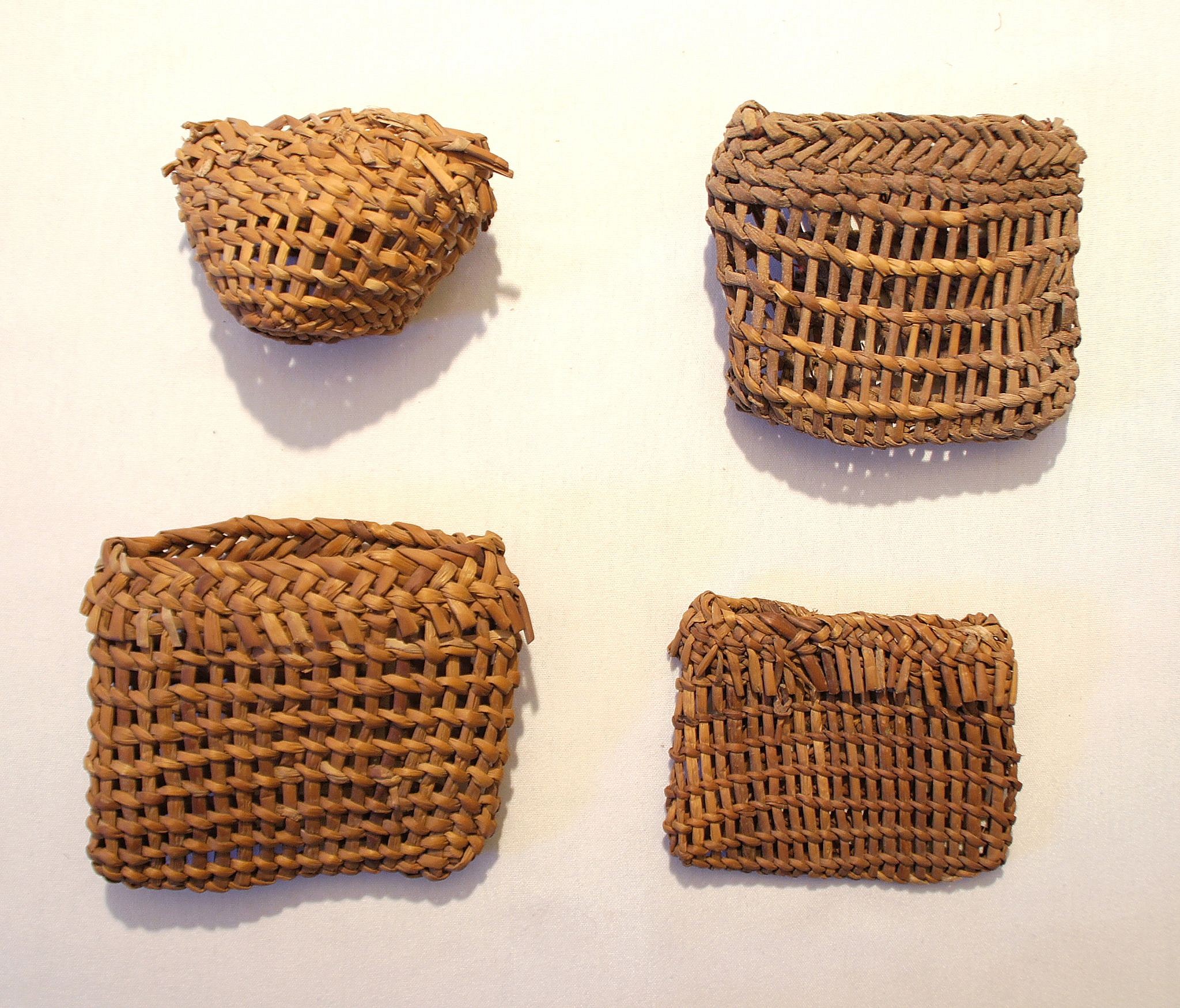 Chile, Eight Twined Baskets For Fishing Line and Hooks
These small baskets made of tule reed were decorated with different patterns.  The baskets were just big enough to hold a hook, line and sinker.  It is possible that all four baskets were made by the same maker.
Media: Wood
Dimensions: Height: 1.25" - 1.75"
N6025