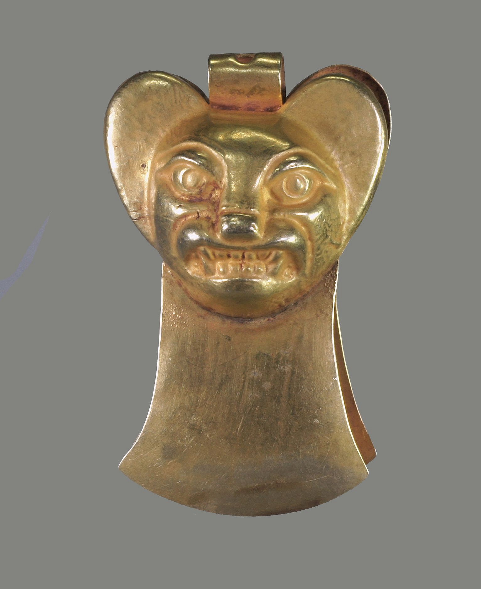 Peru, Moche Gold Tweezers With Embossed Large Eared Bat Face
Pincers have been found from as early as the Vicus period (pre-Moche), circa 300 BC and were thought to be used to pluck facial hair.  Few are known from the Moche period and most of the pincers that have been found were from the Chimu and Inca periods.  This particular pincer has an embossed face of a bat with fanged teeth. This pincer was made from one hammered sheet of high carat gold and embossed twice on a carved wood form of a bat face and bent in the middle.  There is also a suspension hole in the middle.  The blades of the pincer flare out in the form of a Moche back flap. Ex. collection Eduwardo Aldunate, Santiago, Chile-prior to 1970.
Media: Metal
Dimensions: Length: 2 3/8" x Width: 1 1/2"   Weight: 16.6 gramsXRF: Au62.5%, Ag. 34.7%, Cu. 2.5%
$9,750
n7012