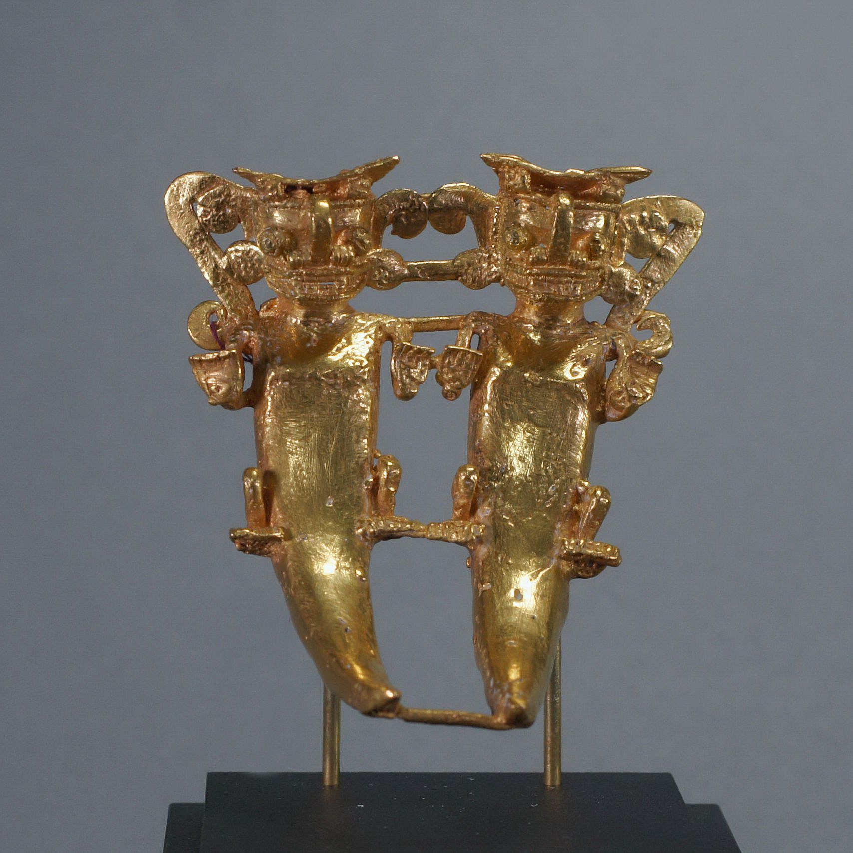 Panama, Cocle Cast Gold Pendant of Pair Anthropomorphized Bats
Lost Was cast depicting paired figures with bat faces, human hands, and a corcodilian body and tail. Duality was a known belief of the natural world: male and female, night and day, heaven and earth. Bats are nocturnal creatures and ruled the darkness.  There are two cast suspension loops behind each outside shoulder. Ex. New York collector, prior to 1970.
Media: Metal
Dimensions: Width 2 3/4" x Length: 3 1/8"  Weight 100.6 gramsXRF
&bull;SOLD
n7027