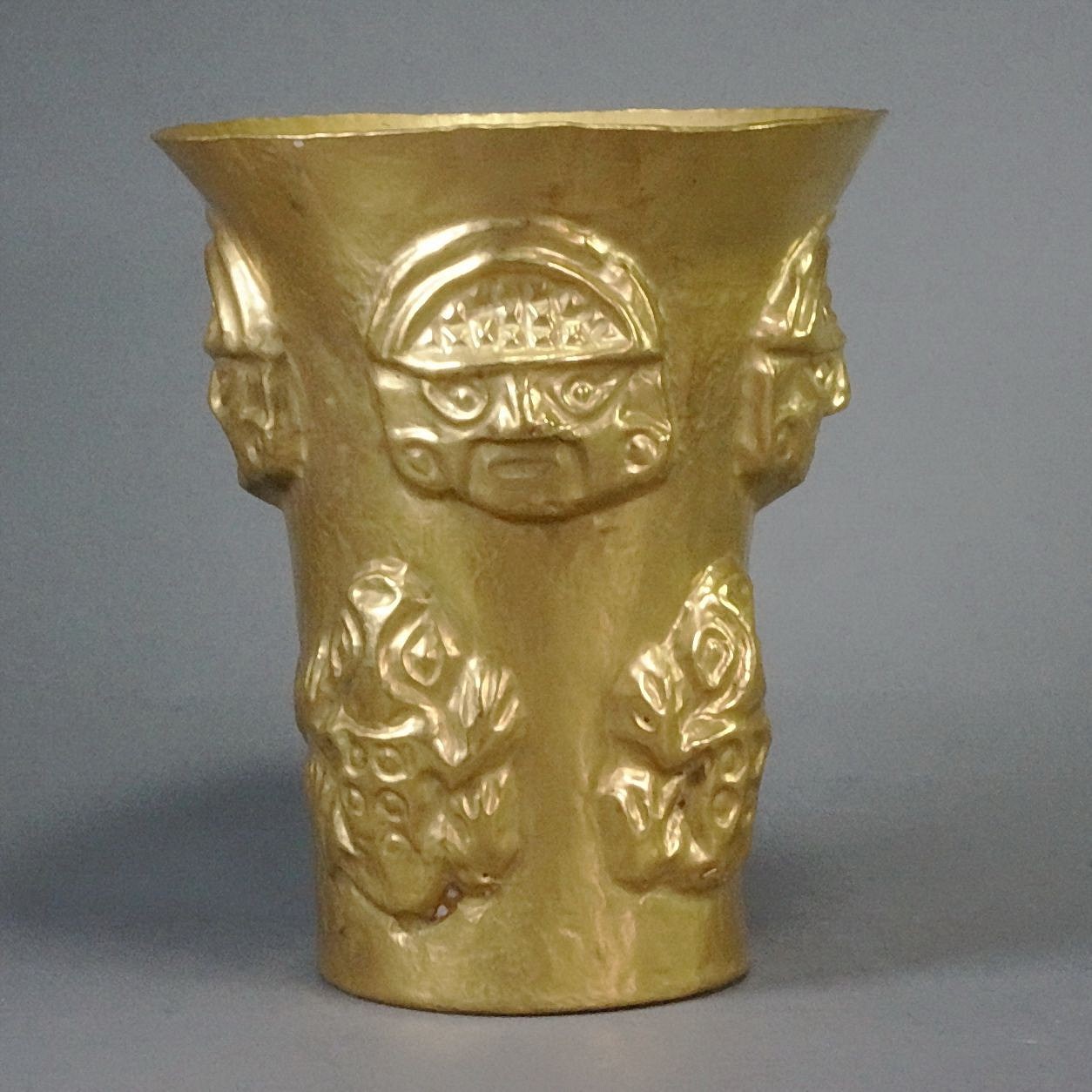 Peru, Sican Gold Beaker with Mask and Frog Motif
The Sican cache of gold came from the largest burial in the Americas at hacienda Batan Grande near the Chimu City of Chan Chan.  These beakers were used to drink the ceremonial Chicha (Corn Beer).  The masks and flared beakers were the most notable objects from this burial.   The beakers came in various designs from frogs to Warriors.   This beaker is unusual in that it has both masks and frog motifs.   Illustrated in THE ART OF PRECOLUMBIAN GOLD, pg.227 the on the right. Exhibited in 1964, Los Angles # 202. Ex-Jan Mitchell collection, prior to 1980.
Media: Metal
Dimensions: Height: 5. 1/8"  Diameter at top: 4 3/8"   Weight:  184 grams
&bull;SOLD
n7054