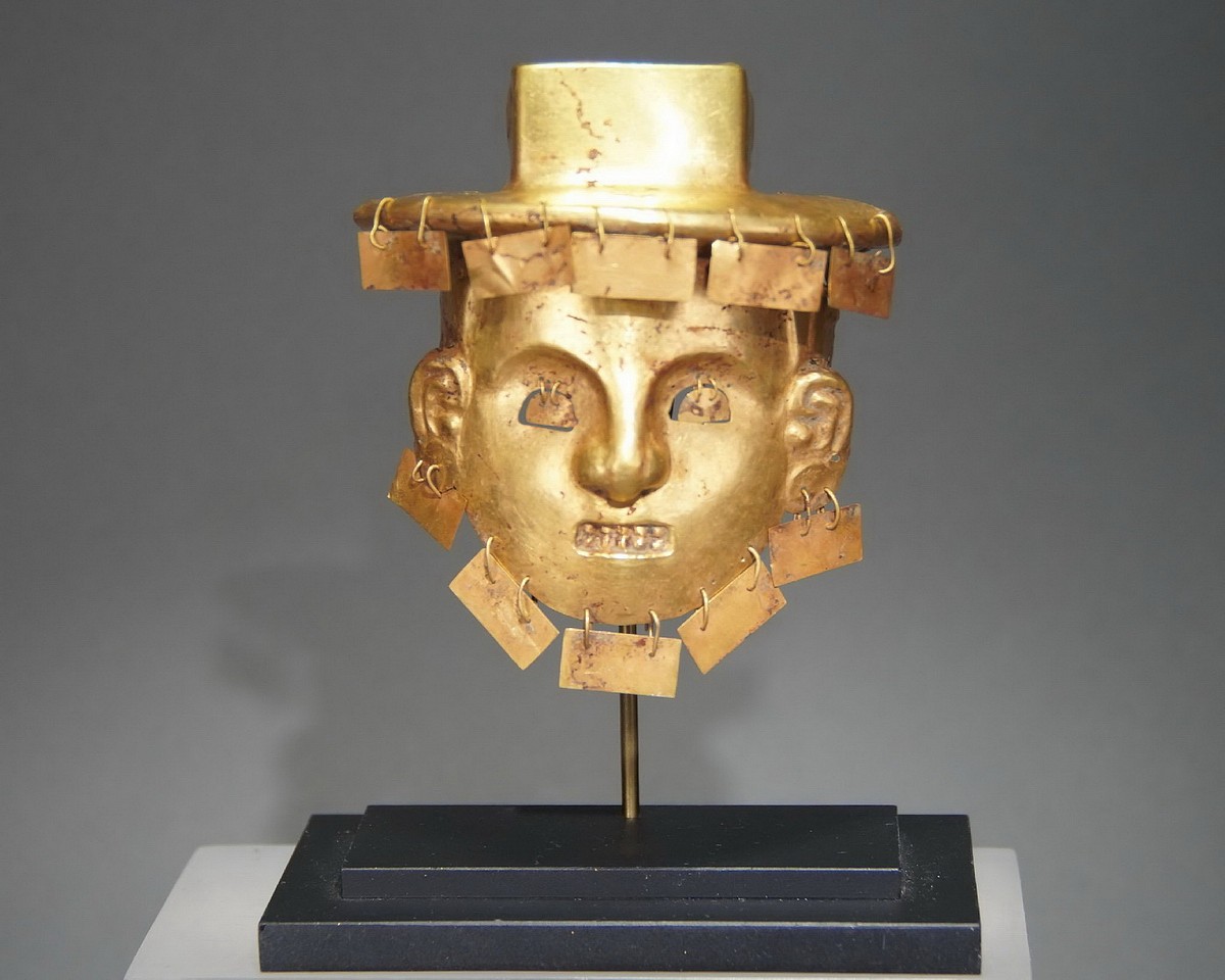 Colombia, Early Calima Gold Forged Maskette of a Deity with Dangles
This is a second type of a Calima face that appears less frequently.  The features are reduced to the essentials: a small, modeled nose and brow, hemispherical eyes, and a rectangular mouth with prominent teeth.  A slightly smaller gold face (9 centimeters) is illustrated in CALIMA AND MALAGANA, by Marianne Cardale Schrimpff, page 170.  There are dangles for the eye, ears, and chin; the illustrated Maskette is missing the eye dangles.  Ex. New York collector, prior to 1970.
Period: Colombia, Calima, Llama Phase, Cauca River Valley, c. 100 BC - AD 400
Media: Metal
Dimensions: Height: 3 3/4"(9.5cm) x  Weight: 39 grams.
Price Upon Request
P1005