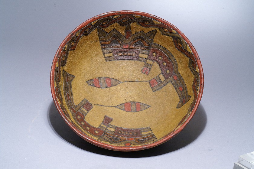 Peru, Paracas Ceramic Dish with Two Cats
Paracas ceramicists decorated much of their pottery with incised designs painted with post-fire fugitive pigments. In this example, two reclining felines adorn the interior sides of the bowl each holding a fruit or vegetable. Because of its relatively large size it suggests that it is Manioc, which is highly nutritious. Feline motifs and geometric images were common in early Paracas pottery. (Sawyer 1966: 108-109). On the outside of the bowl is a wide band in dark green with diamonds in alternating colors.  Dawson identifies this design as Middle Phase Ocucaje 8 due to the facial details on the felines and the flared tail tips.
Very similar cats are illustrated in THE PARACAS POTTERY OF ICA, PAGE 359 & 360 figures 41 b& 42b.Acquired by David Bernstein in 2006. Period: Peru, Paracas, Ocucaje Phase 7, Ica valley, South Coast, c. 300 - 200 BC
Media: Ceramic
Dimensions: Diameter: 6 1/4" x  Height: 2 3/4"
$6,500
M6086
