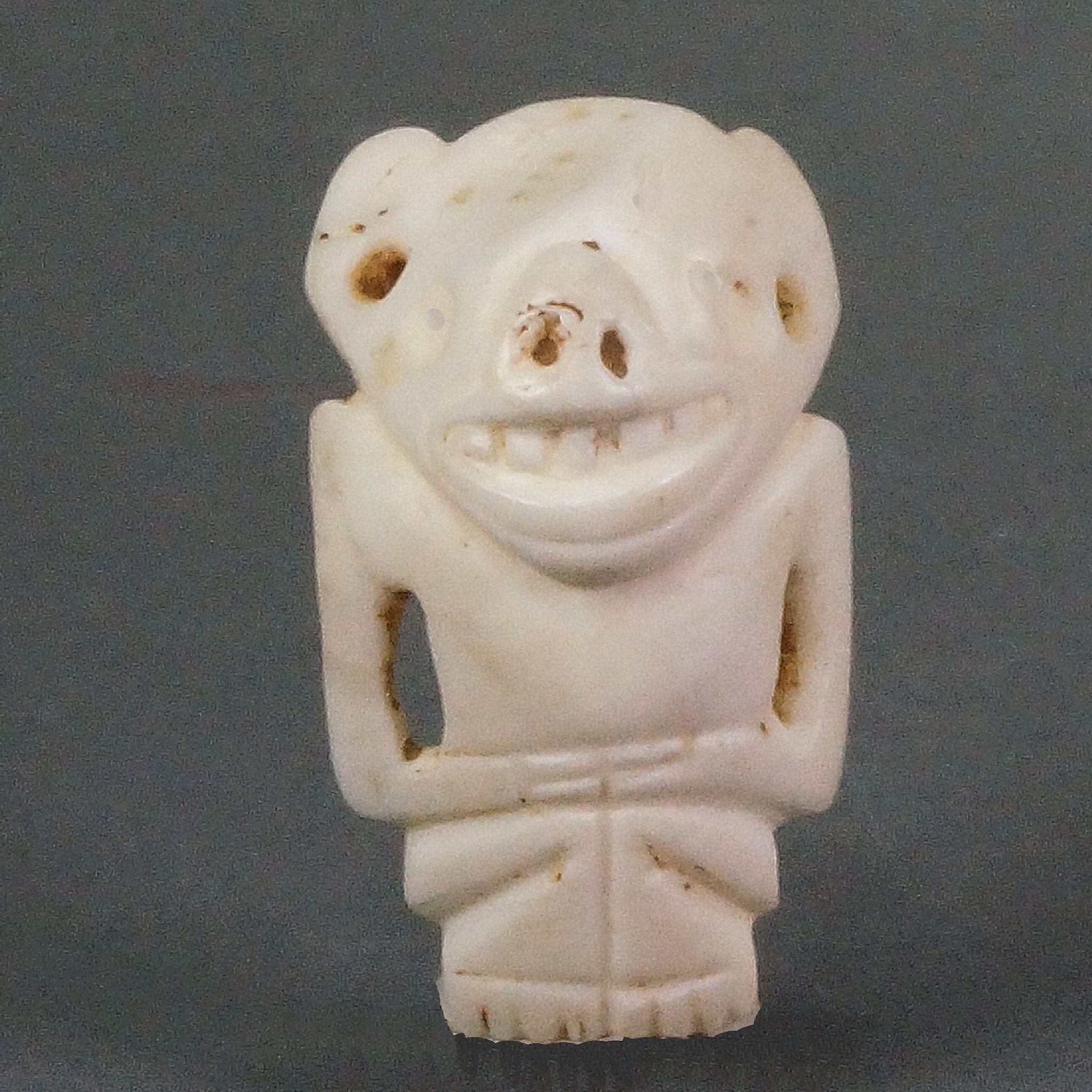 Dominican Republic, Taíno Carved Shell Amulet of a Figure with a Bat Face
This bat deity amulet features a stylized human figure with bat-like features, such as large ears and a pug nose.  There are two suspension holes below each ear.  This amulet was likely originally the central bead on a larger beaded necklace.
Media: Shell
Dimensions: Height: 1 1/2"
$2,250
98149