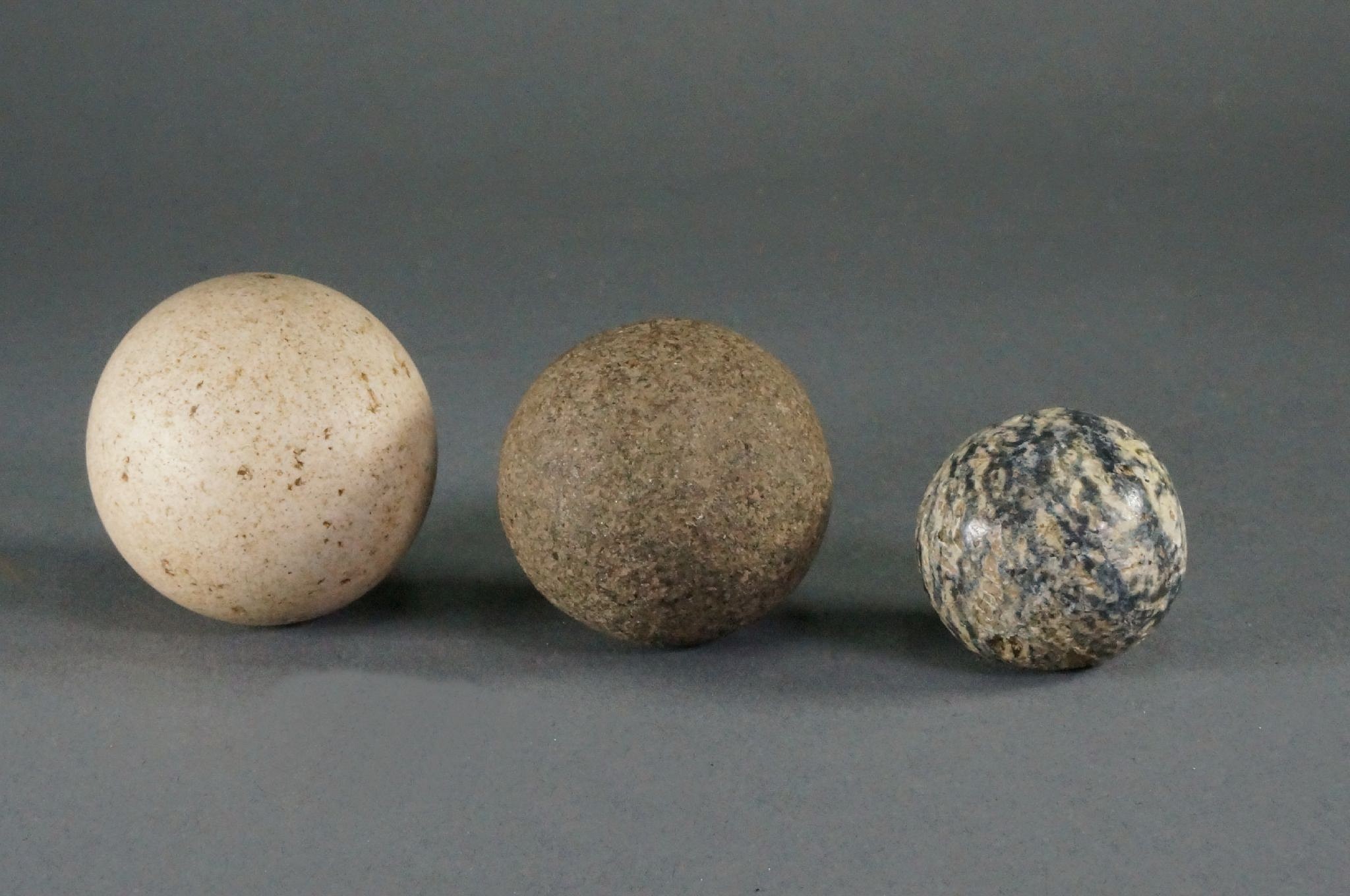 Dominican Republic, Three Small Taíno  Stones Balls Different Stones
These stones are graduated in size, and of different colors: white, grey, brown, and marbleized.  Special care was taken to make these stones perfectly round.  These small stones have been found in tombs of small children, with the largest stones buried along with the older children.  These stones may also have been used as projectiles for slings.
Period: Dominican Republic, Taíno , Early Classic Period, c. AD 600 - 1000
Media: Stone
Dimensions: Diameter: 9.5" & 1.3"
98500