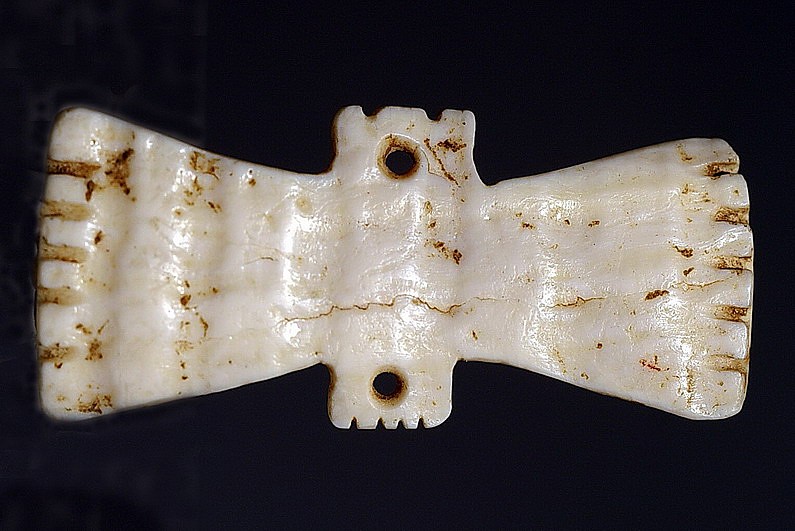 Dominican Republic, Taíno  Shell Ornament in the Form of a Double Bat
The circular mouth openings in each bat head suggest that this ornament was sewn onto a garment or headband. Bats were considered to be messengers of the dead from the otherworld, and clothing appliquÃ©s such as this represented the spirit of a revered ancestor.
Period: Dominican Republic, Taíno , c. AD 1000 - 1500
Media: Shell
Dimensions: Length: 1 1/2"
99335