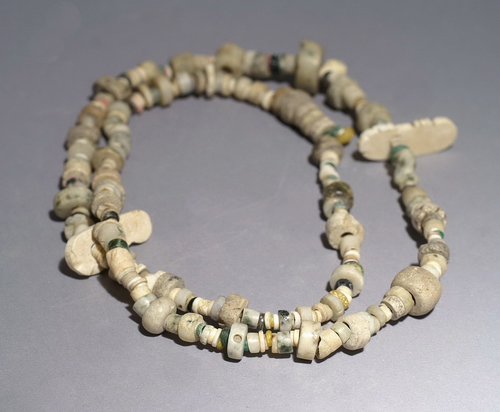 Dominican Republic, Taíno  Necklace with a Variety of Carved Discoidal Shell and Stone Beads
The shell and stone beads in this necklace are varied in size, material, and color, including several rare miniature turquoise beads.  There are several carved shell beads known as llaves, or key-shaped forms.  All the stones were drilled and polished.  The Taíno  artists were known for their miniature stone works, including beads, amulets, axes, and even miniature three-pointers (zemis).
Period: Dominican Republic, Taíno , c. AD 1000 - 1500
Media: Stone
Dimensions: Necklace Length: 26"  Beads range in diameter: 1/10" to 1/2"
99391